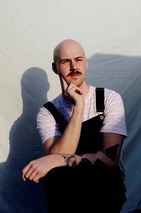 Bald man sitting in front of white backdrop