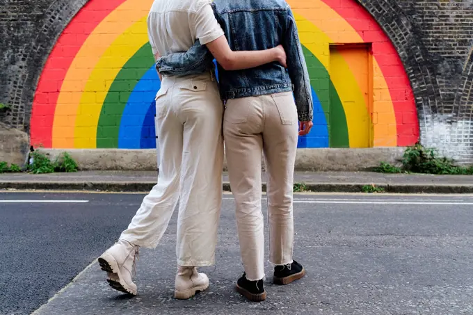 Gay couple in front of rainbow colored wall