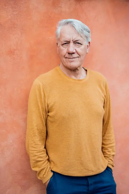 Smiling senior man standing with hands in pockets