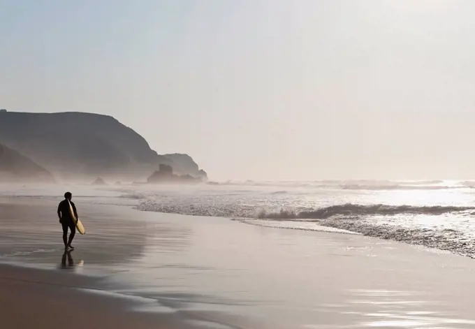 Portugal, Surfer walking on beach