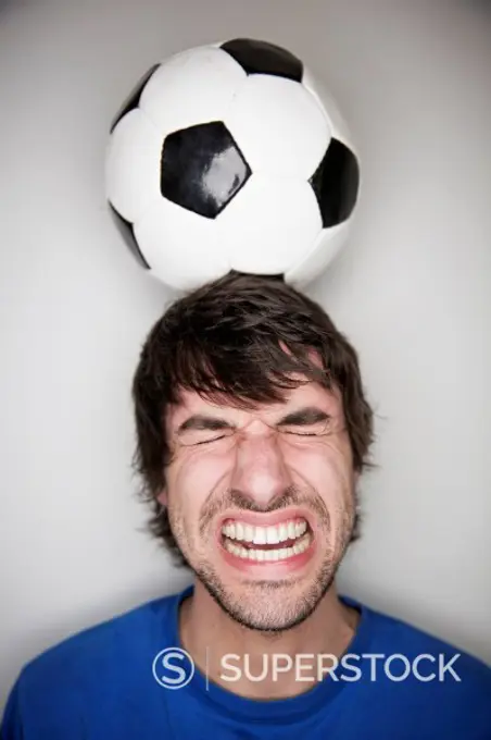 Young man balancing soccer ball on head