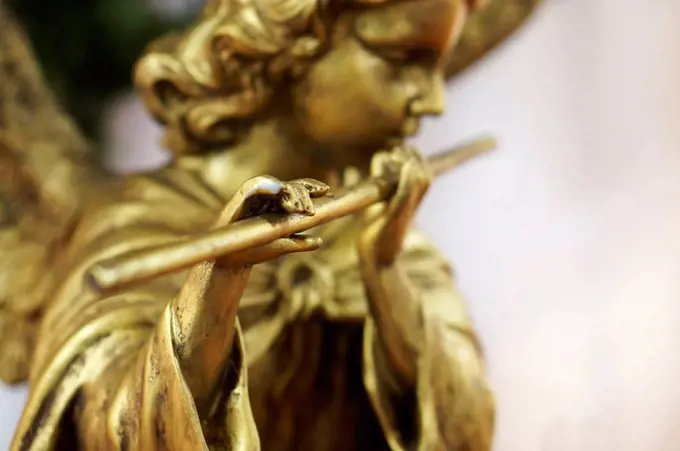 Golden angel figurine playing flute, close up