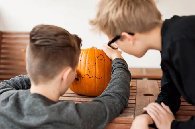 Two boys preparing a pumpkin for Halloween lantern
