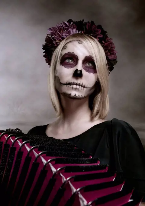 Portrait of woman with sugar skull makeup and accordion