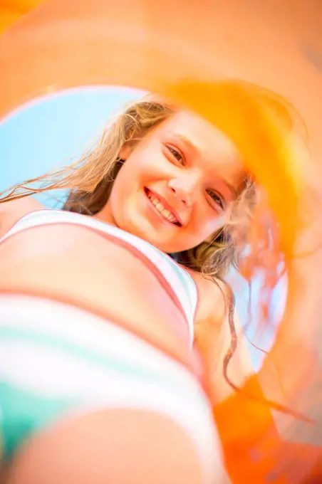 Smiling girl on beach holding an orange floating tyre