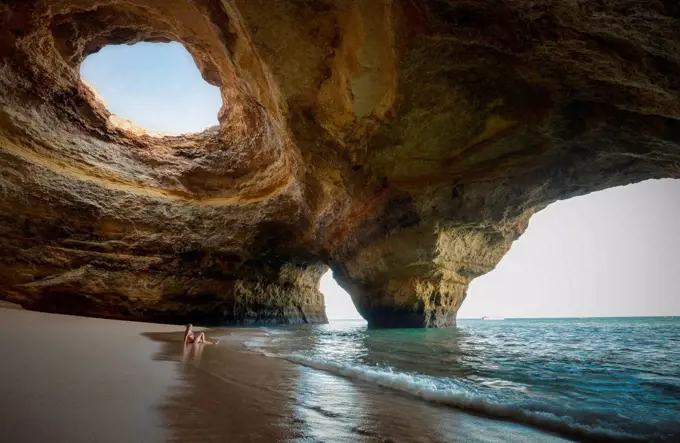 Portugal, beach of Benagil, cave, woman sitting at seafront