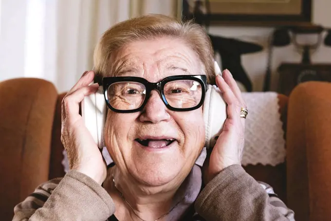 Portrait of happy elderly lady hearing music with headphones