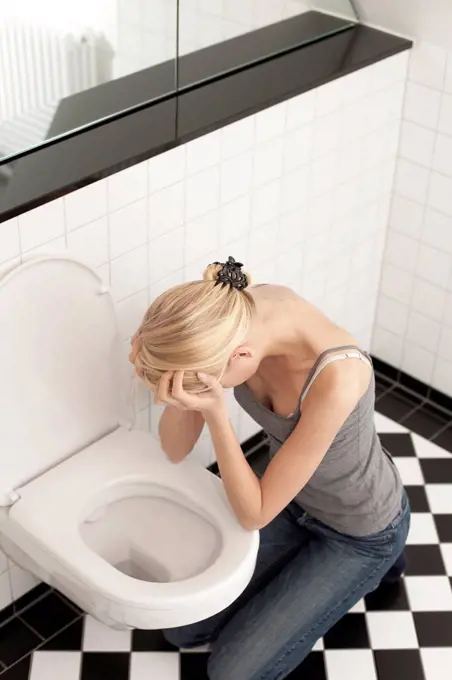 Despaired anorexic young woman at the toilet