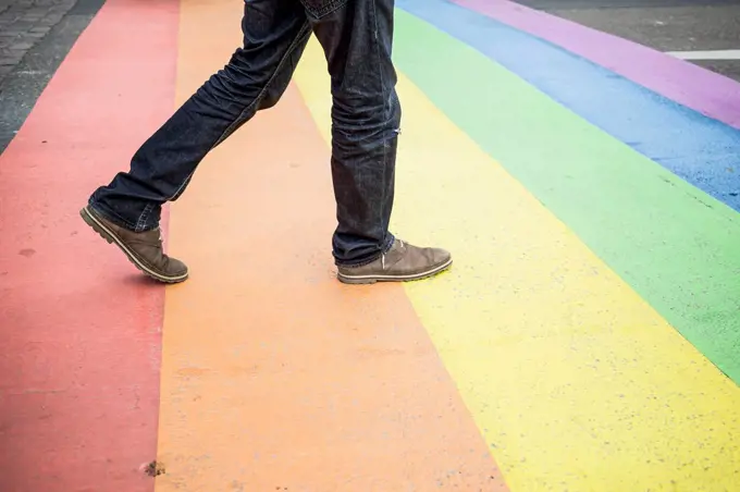 Netherlands, Maastricht, man walking on rainbow flag painted on the street