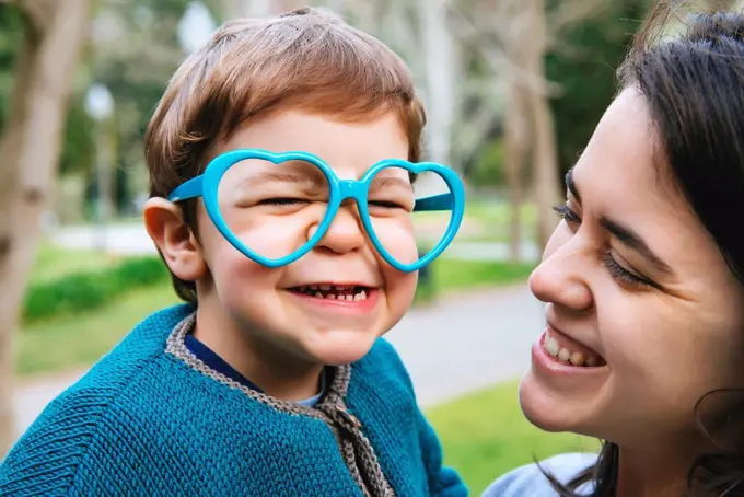 Portrait of little boy making faces with heart shaped glasses