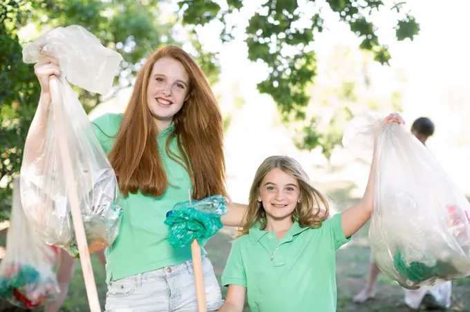 Portrait of two smiling girls showing picked up garbage
