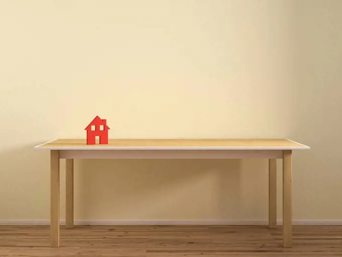 House model on empty table against plain wall