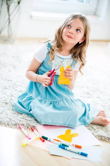 Little girl cutting out paper Easter bunnies