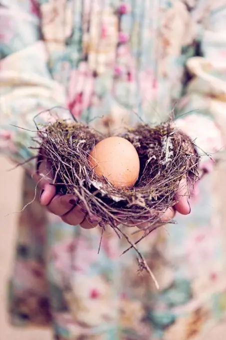 Girl holding an egg in a nest