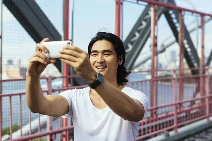 USA, New York City, man on Williamsburg Bridge in Brooklyn taking a selfie