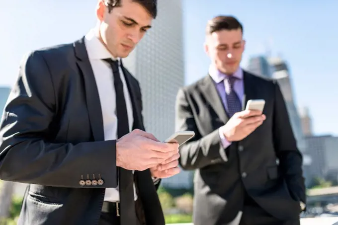 USA, Los Angeles, two businessmen looking at cell phones