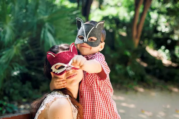 Mother and little son with animal masks playing in the park