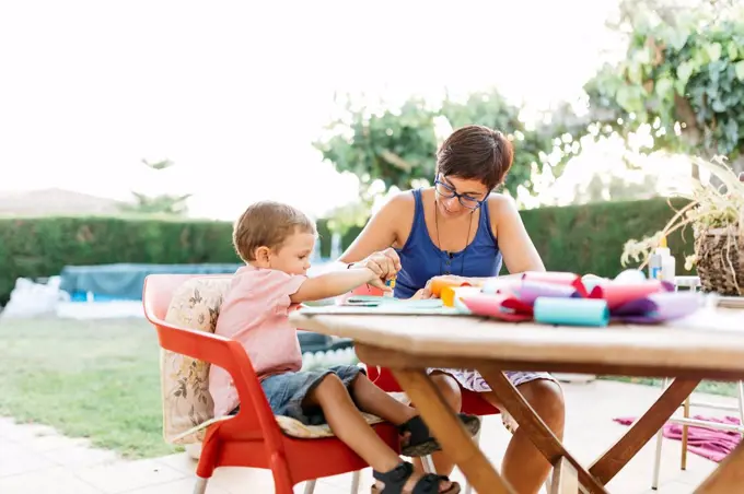 Mother and son doing handicrafts at garden table