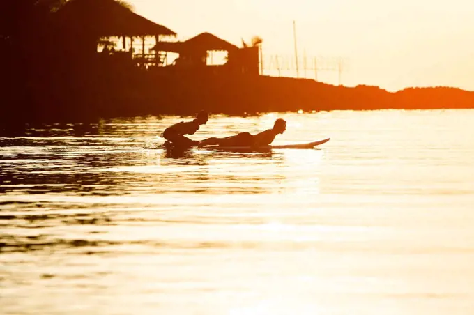 Thailand, couple doing yoga on paddleboard at sunset, cobra pose