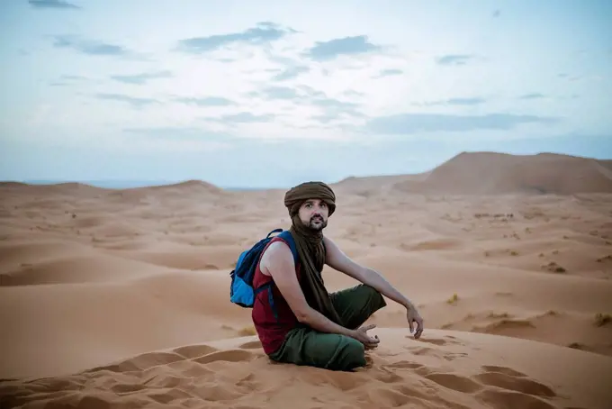 Tourist wearing turban sitting in the desert