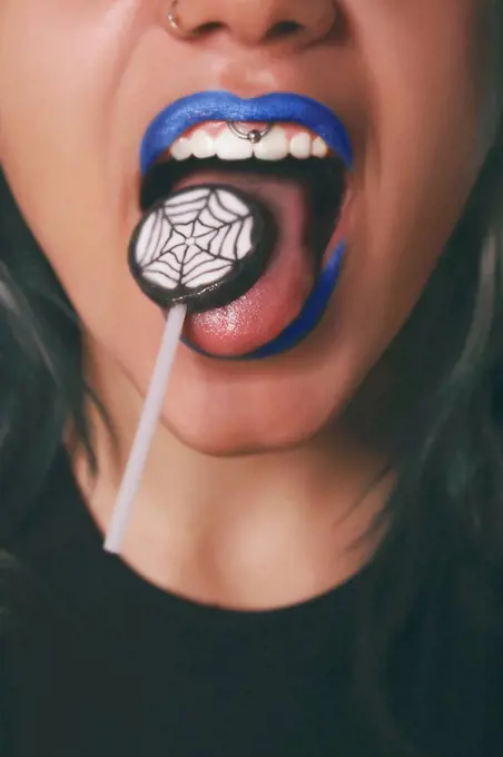 Woman licking Halloween lollipop, close-up