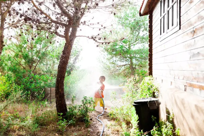 Little boy playing with garden hose