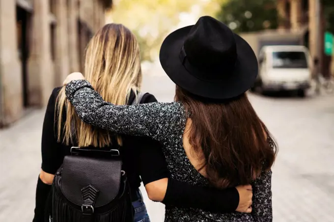 Back view of two women walking on the street