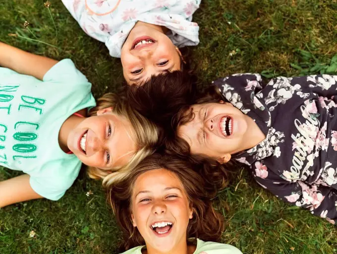 Four laughing girls lying head to head on a meadow