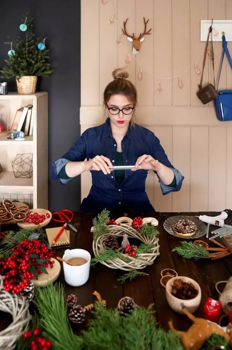 Woman taking picture of self-made Advent wreath with smartphone