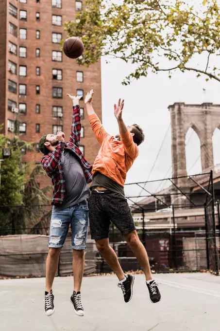 USA, New York, two young men playing basketball on an outdoor court