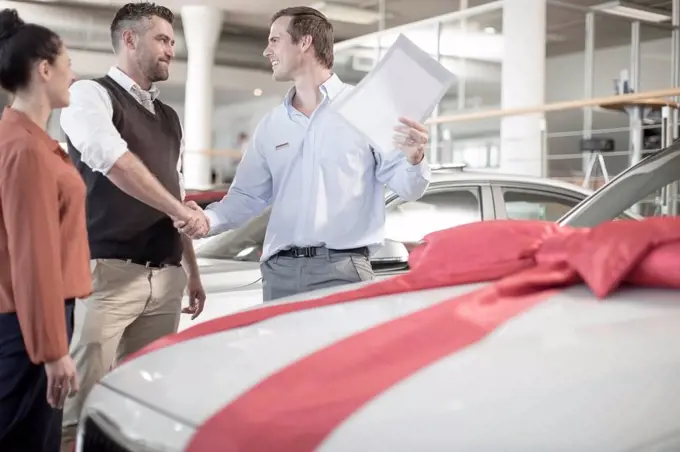 Car dealer shaking hands with man in car dealership