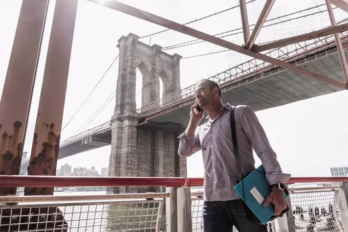 USA, New York City, man at East River talking on cell phone