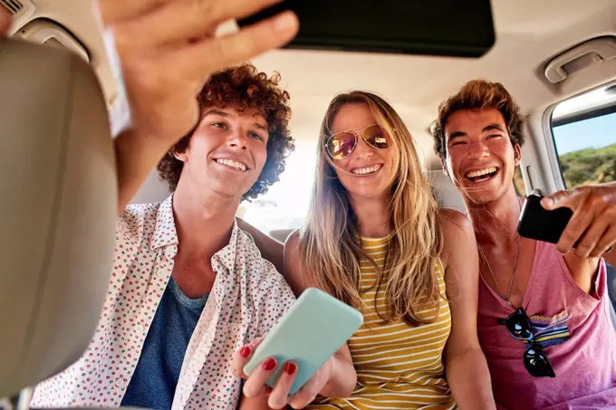 Happy friends in a car taking a selfie
