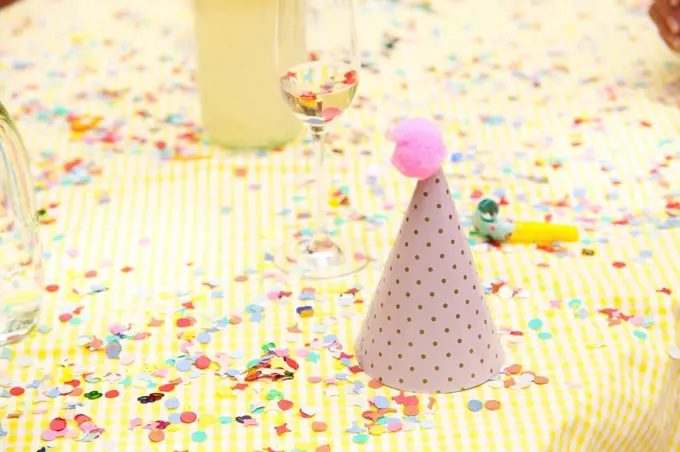 Party hat and party blower on table with confetti