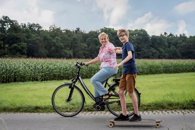 Grandson and grandmother riding bicycle and skateboard together
