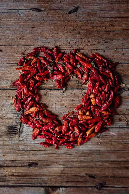 Heart shaped with red dried chili pods on wood