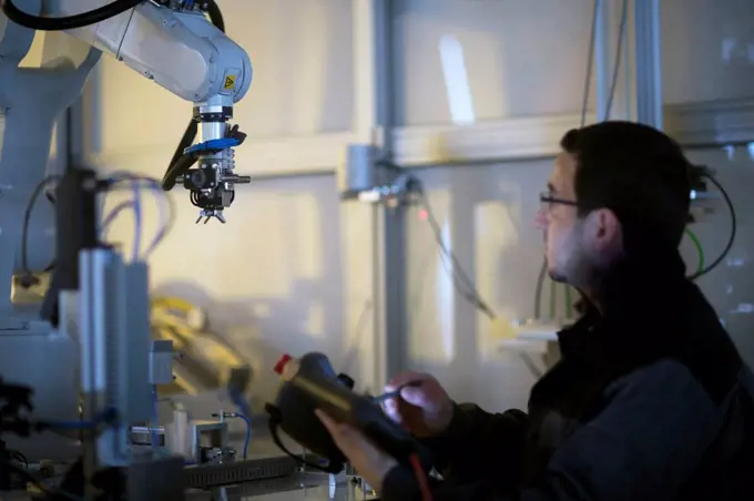 Man looking at robot arm in a sensor technology plant