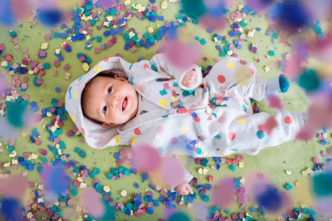 Happy baby girl surrounded by confetti