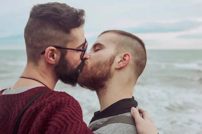 Gay couple kissing in front of the sea