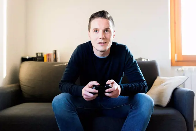 Man sitting on the couch playing with games console