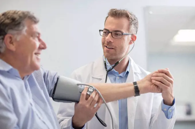 Doctor taking blood pressure of senior patient in medical practice