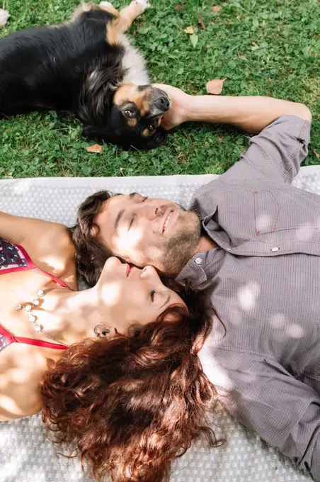 Couple in love with dog lying on a blanket
