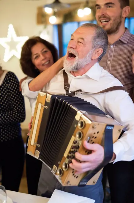 Senior man playing accordion for happy family at Christmas