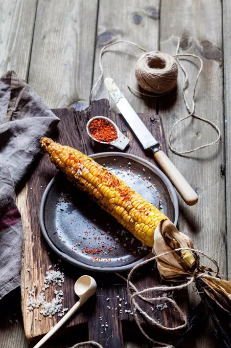 Grilled corncob with butter, salt and chili flakes on plate