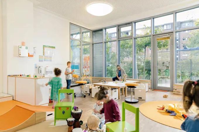 Pre-school teacher and children in playing in learning room in kindergarten
