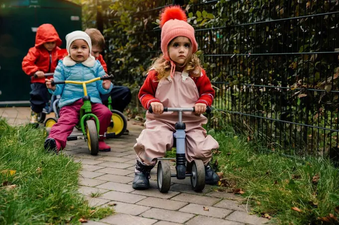 Children using scooters in garden of a kindergarten