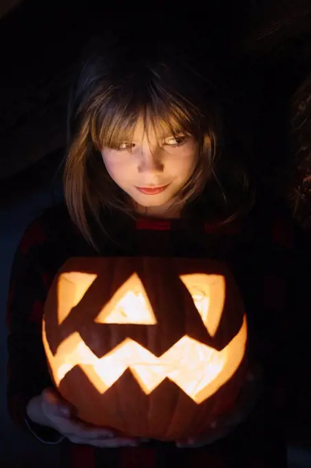 Portrait of girl with lighted Jack O'Lantern at Halloween