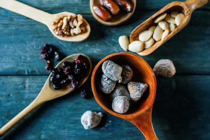Wooden spoon of dried figs and nuts and other dried fruits in the background