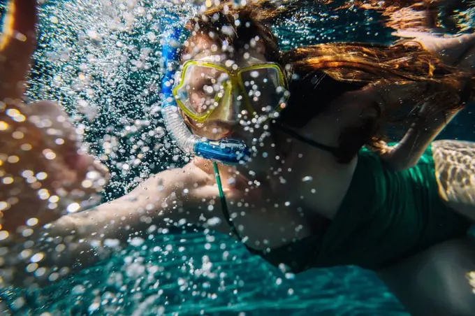 Portrait of woman with diving goggles and snorkel underwater in a swimming pool