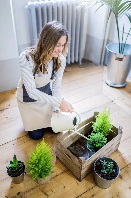 Smiling woman at home watering plants